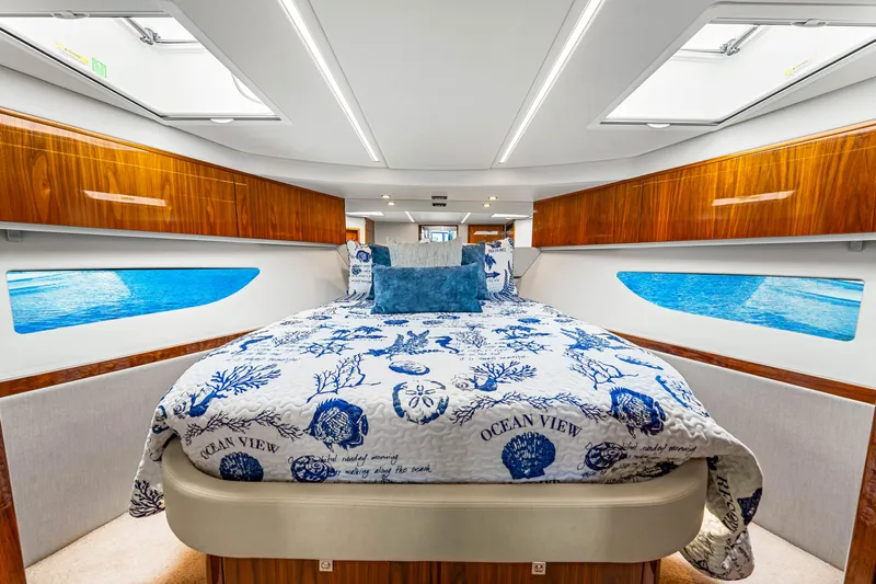  Yacht Photos Pics Luxurious bedroom interior of 2022 Riviera 505 SUV yacht with ocean-themed bedding.