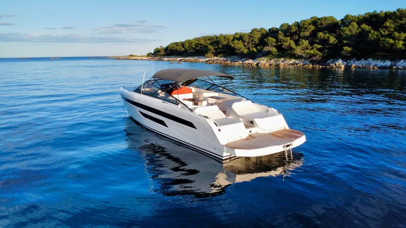 Ischia Yacht Photos Pics 2024 BB Yachts 44 Ischia cruising on serene blue waters near a lush, tree-lined shore.