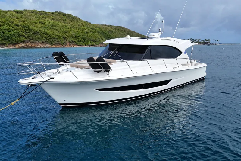  Yacht Photos Pics 2020 Riviera 395 SUV yacht anchored in clear blue water near lush green island.