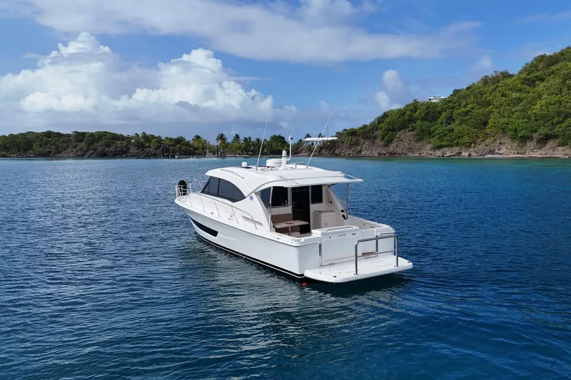  Yacht Photos Pics 2020 Riviera 395 SUV yacht on serene blue waters near lush green coastline.