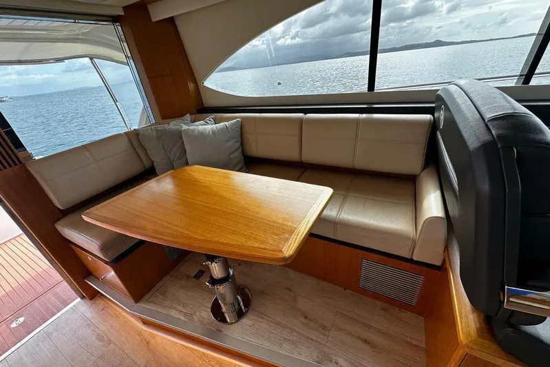  Yacht Photos Pics Interior of 2020 Riviera 395 SUV with elegant seating and wooden table, overlooking the ocean.