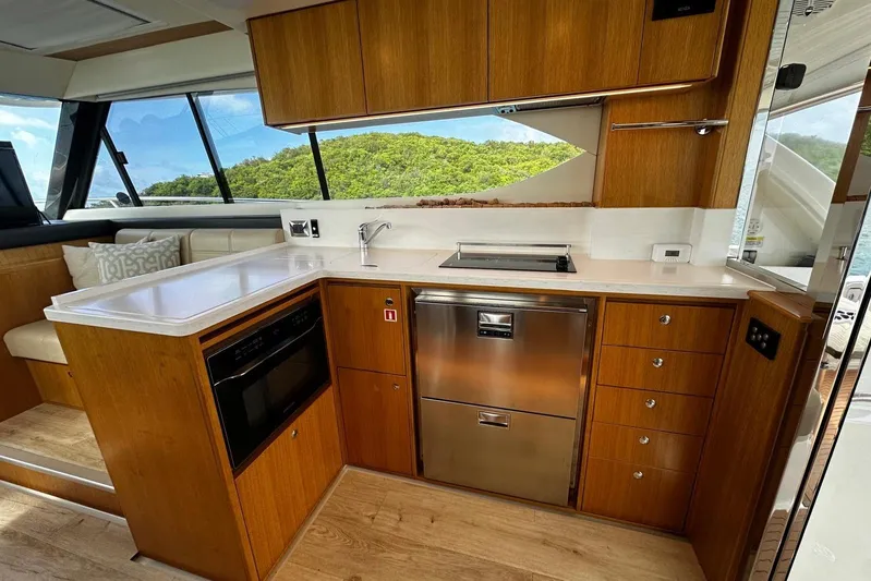  Yacht Photos Pics Modern kitchen interior of 2020 Riviera 395 SUV yacht with wood cabinetry and stainless steel appliances.