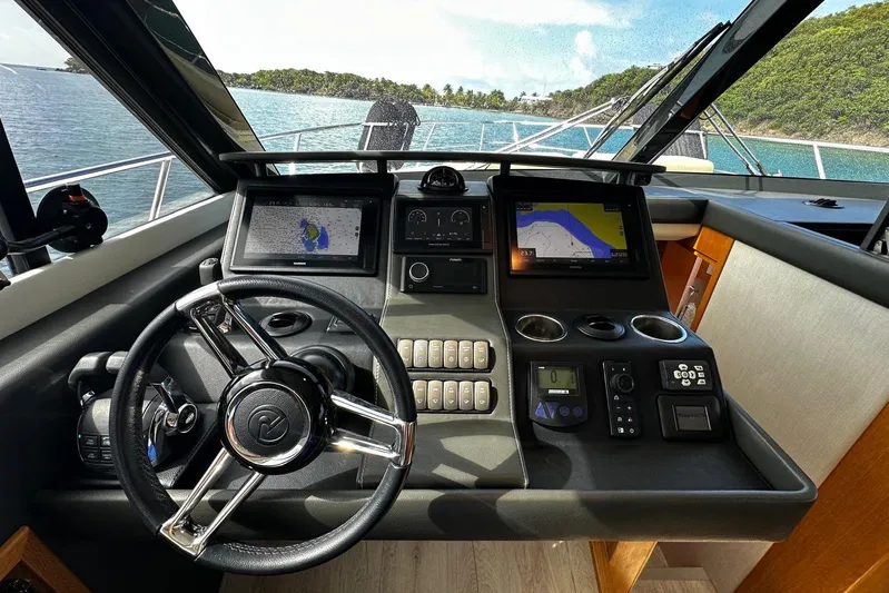  Yacht Photos Pics 2020 Riviera 395 SUV helm with navigation screens and steering wheel, overlooking scenic waters.