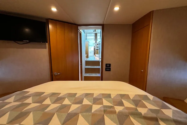  Yacht Photos Pics Interior of 2020 Riviera 395 SUV bedroom with geometric bedspread and wall-mounted TV.