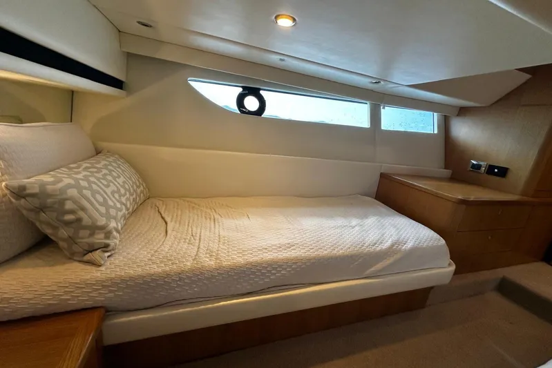  Yacht Photos Pics 2020 Riviera 395 SUV cabin interior with bed, window, and wooden cabinetry.
