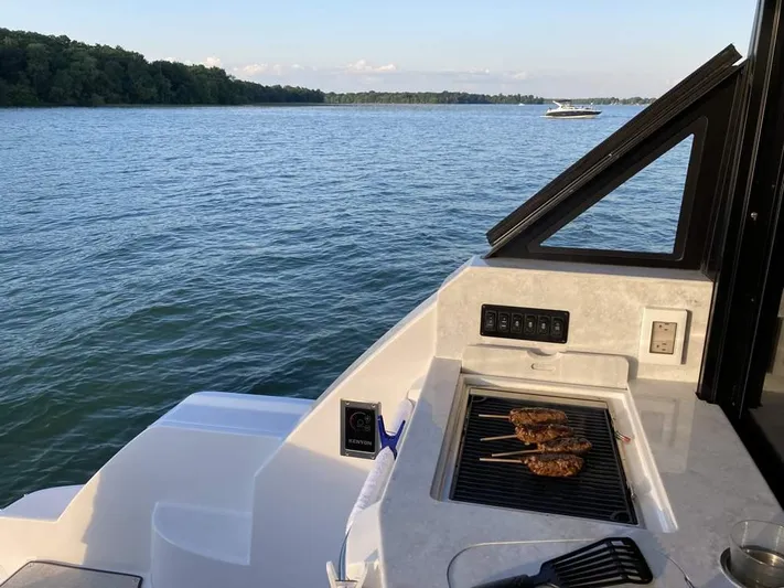  Yacht Photos Pics 2021 Regal 38 Grande Coupe with onboard grill, cruising on a serene lake.