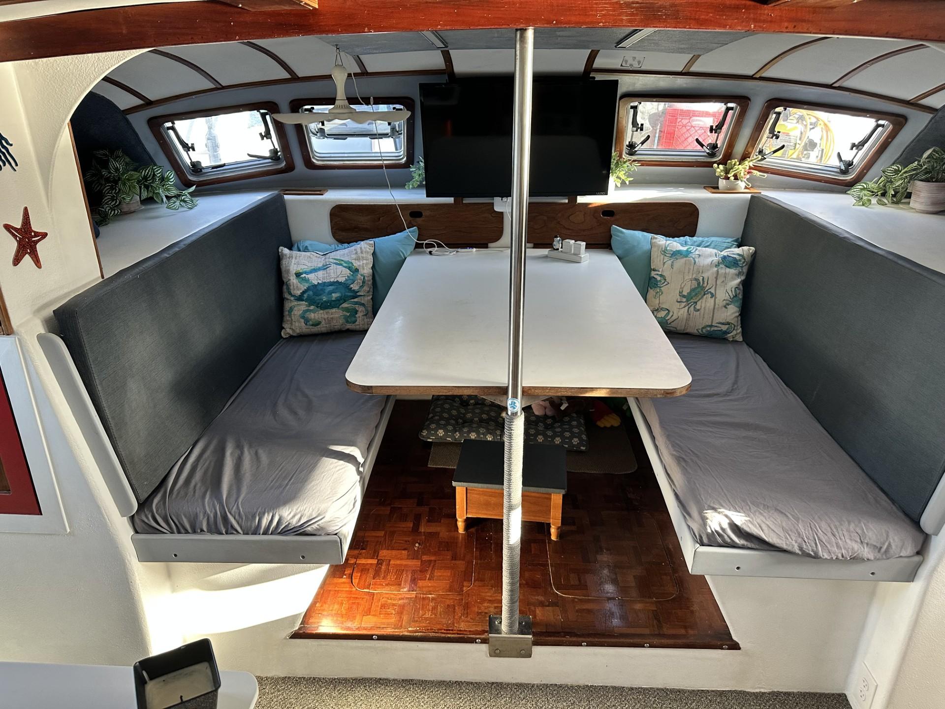 Interior of a 1972 Custom 53 Catamaran with cozy seating and a central table.
