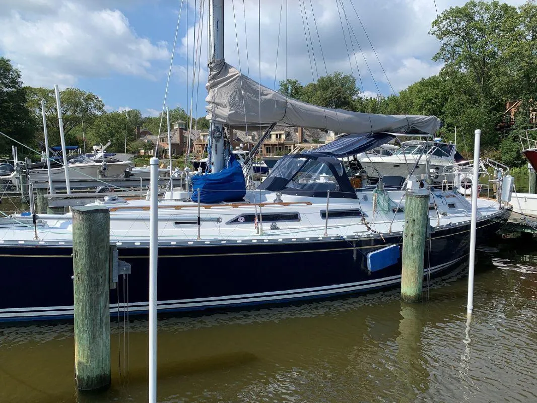 Sailboat docked at marina, Hylas 44 model, 1990, with blue hull and covered sails.