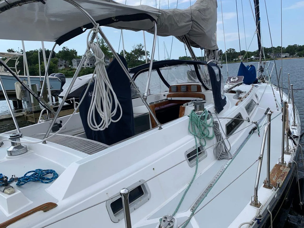 Sailboat Hylas 44, 1990 model, docked with ropes and canopy, on a calm waterway.