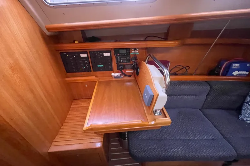  Yacht Photos Pics Navigation station in a 2005 Hunter 38 sailboat with control panels and seating.