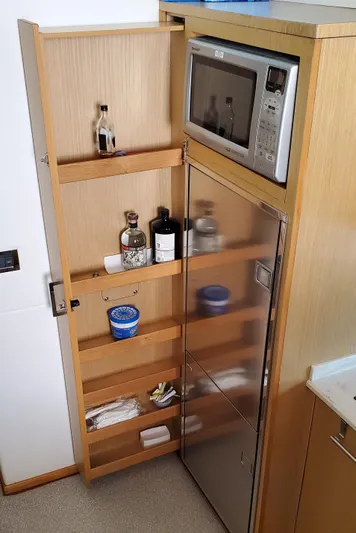 Never Again Yacht Photos Pics 2012 Sea Ray 450 Sedan Bridge kitchen with microwave, storage shelves, and stainless steel fridge.