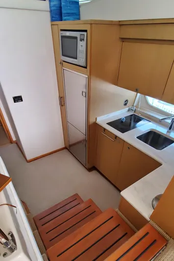 Never Again Yacht Photos Pics 2012 Sea Ray 450 Sedan Bridge kitchen with microwave, sink, and wooden cabinetry.