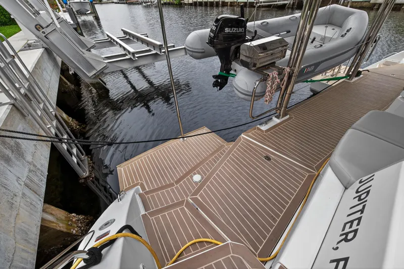 Sundecker Yacht Photos Pics Leopard 45 yacht deck with dinghy and Suzuki motor, docked in a marina.