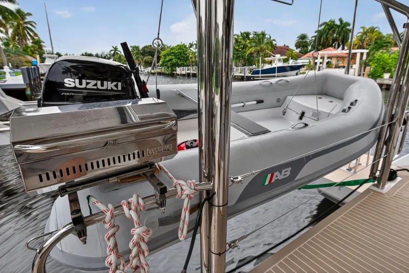 Sundecker Yacht Photos Pics Inflatable boat with Suzuki motor on Leopard 45, 2021 model, docked near lush greenery.