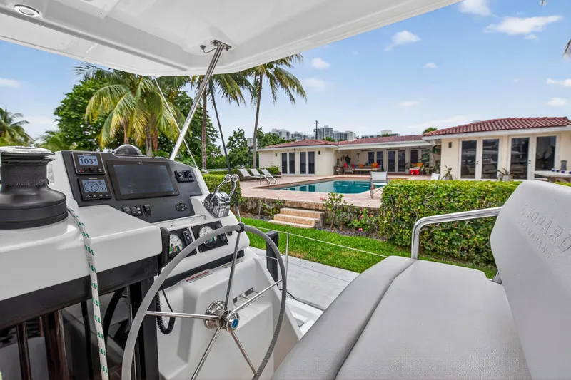 Sundecker Yacht Photos Pics Helm of 2021 Leopard 45 catamaran overlooking luxurious poolside villa with palm trees.