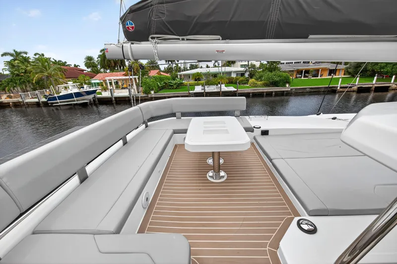 Sundecker Yacht Photos Pics 2021 Leopard 45 yacht deck with seating and table, docked by waterfront homes.