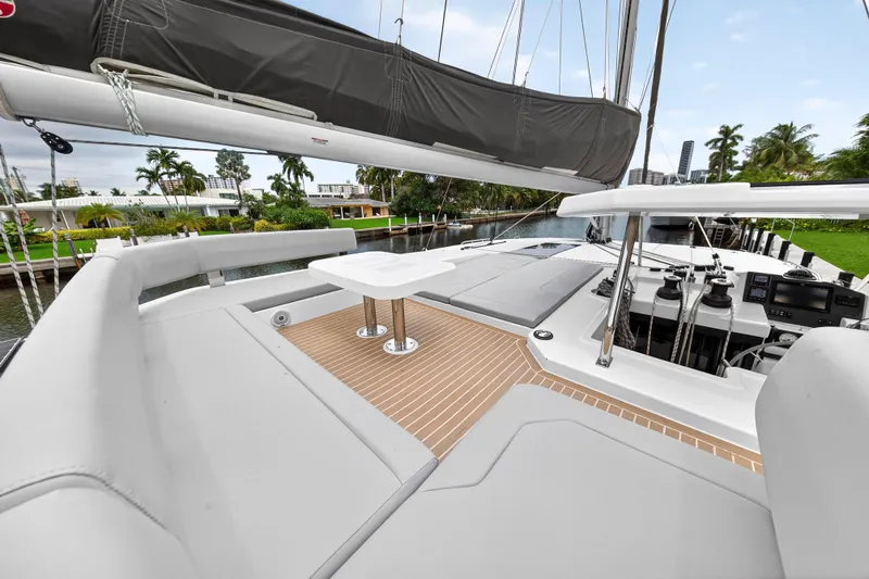 Sundecker Yacht Photos Pics Luxurious 2021 Leopard 45 yacht deck with seating and table, docked by palm trees.