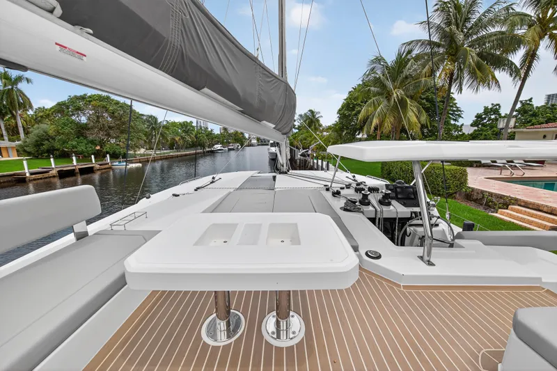Sundecker Yacht Photos Pics 2021 Leopard 45 yacht deck with seating, docked by a canal with palm trees.