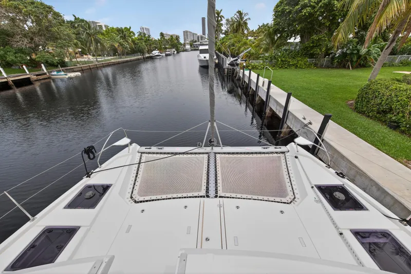 Sundecker Yacht Photos Pics Front view of a 2021 Leopard 45 catamaran docked in a scenic canal.