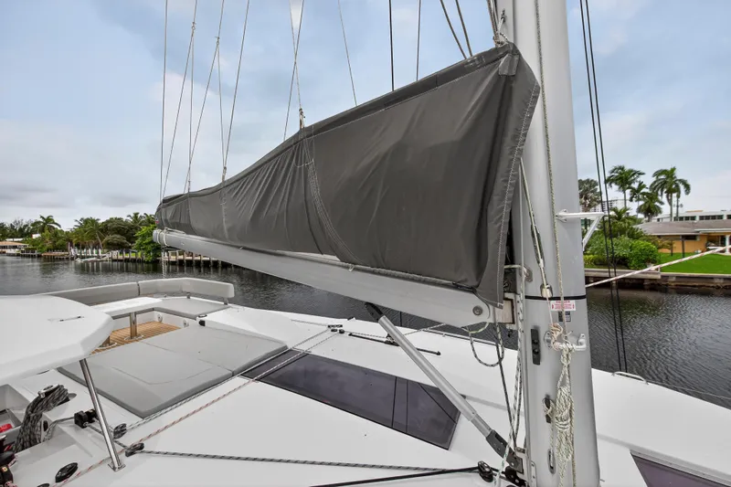 Sundecker Yacht Photos Pics 2021 Leopard 45 yacht with sail cover, docked by a scenic waterfront.