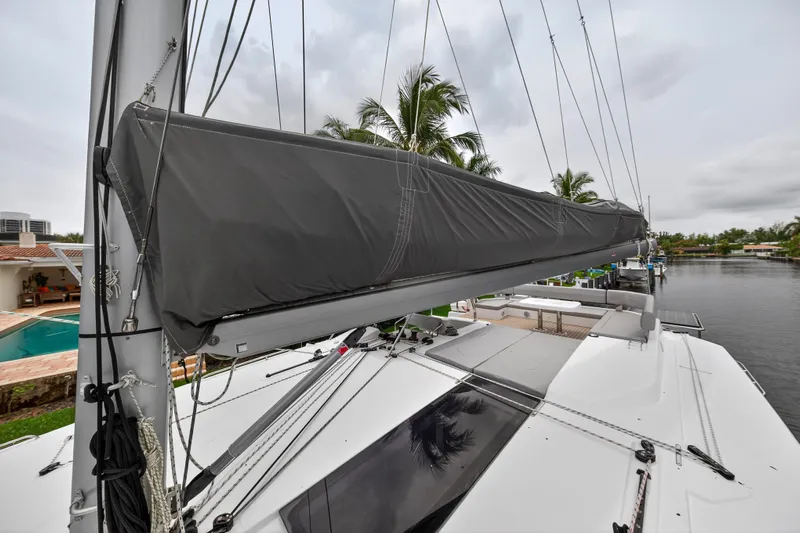 Sundecker Yacht Photos Pics 2021 Leopard 45 catamaran with covered sail, docked near palm trees and waterfront homes.