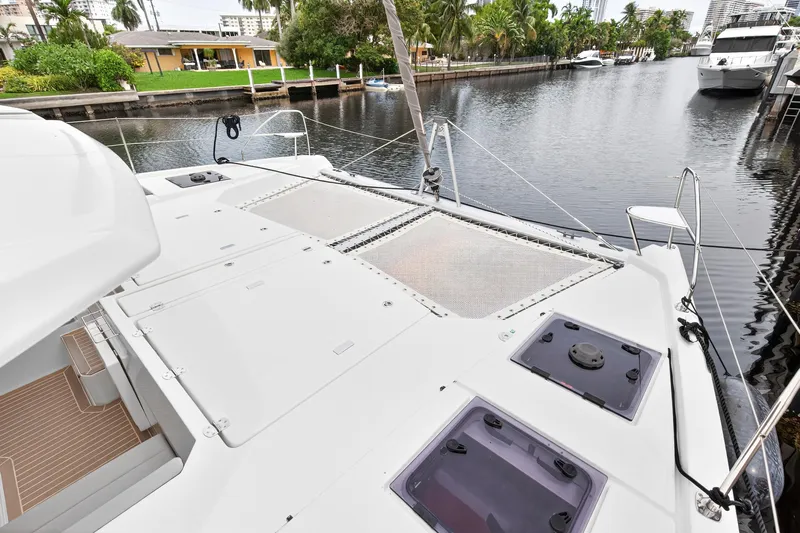 Sundecker Yacht Photos Pics 2021 Leopard 45 catamaran deck view, docked by a scenic canal with lush greenery.