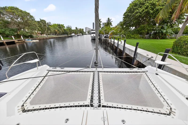 Sundecker Yacht Photos Pics Front view of 2021 Leopard 45 catamaran docked by lush greenery.