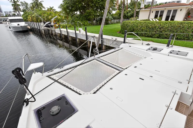 Sundecker Yacht Photos Pics Leopard 45 catamaran docked by waterfront home, showcasing spacious deck and lush surroundings.