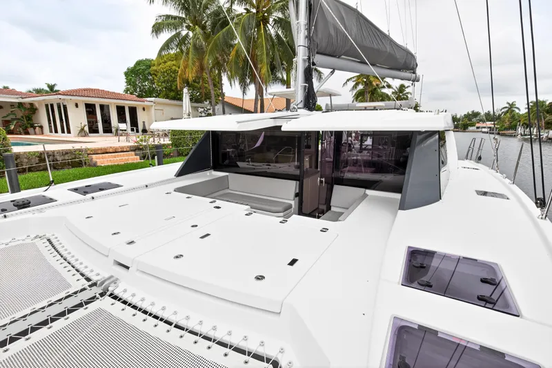 Sundecker Yacht Photos Pics 2021 Leopard 45 catamaran docked by waterfront home with palm trees.