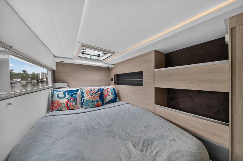 Sundecker Yacht Photos Pics Modern bedroom interior on 2021 Leopard 45 yacht, featuring cozy bed and nautical-themed pillows.