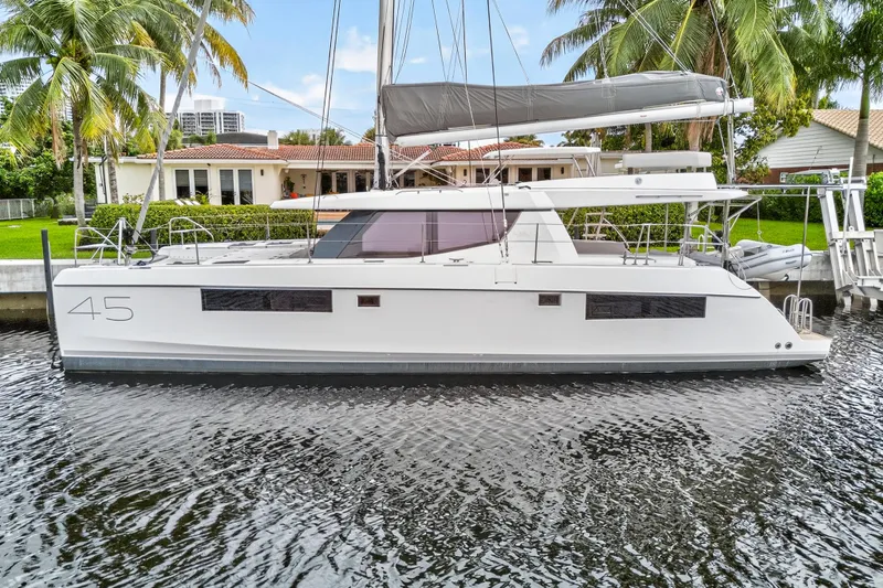 Sundecker Yacht Photos Pics 2021 Leopard 45 catamaran docked by waterfront home with palm trees.