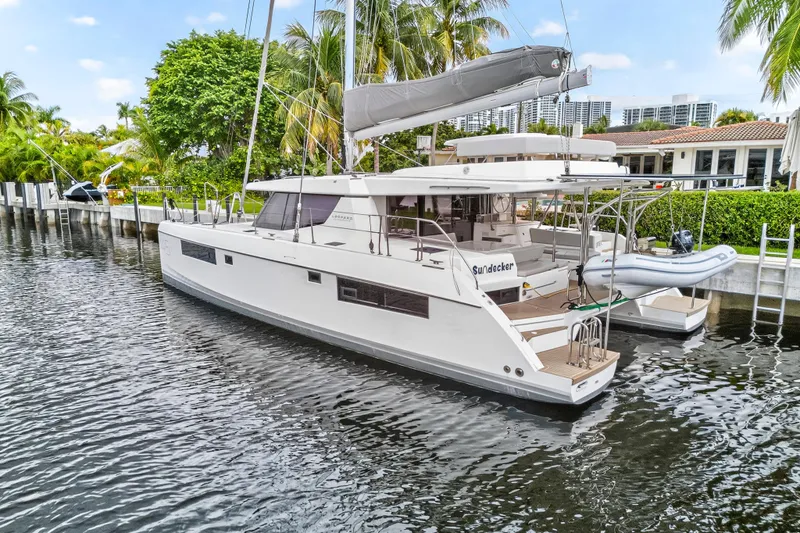 Sundecker Yacht Photos Pics 2021 Leopard 45 catamaran docked in a scenic waterfront setting with lush greenery.