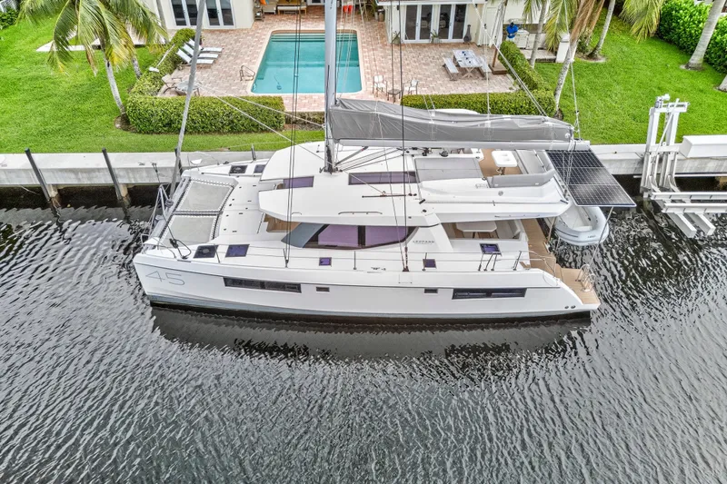 Sundecker Yacht Photos Pics Aerial view of a 2021 Leopard 45 catamaran docked by a waterfront property.