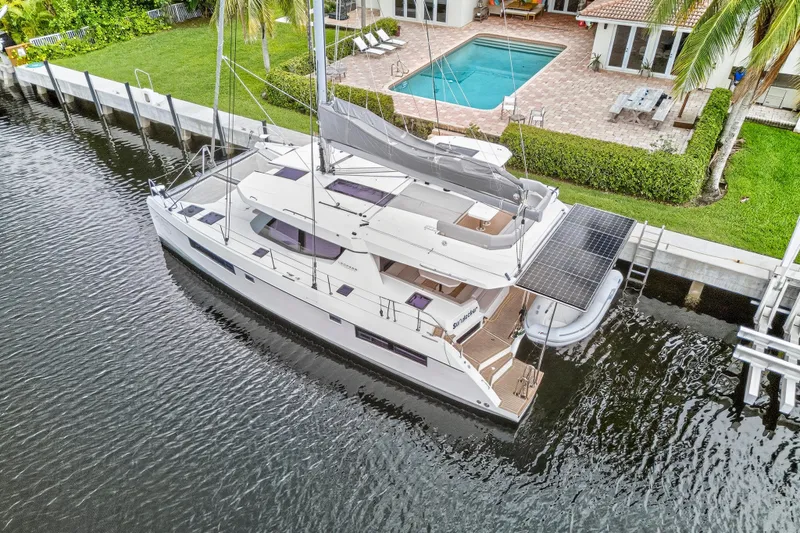 Sundecker Yacht Photos Pics Luxury Leopard 45 catamaran docked by a waterfront home with pool, 2021 model.