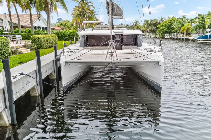 Sundecker Yacht Photos Pics 2021 Leopard 45 catamaran docked by lush waterfront, surrounded by palm trees.