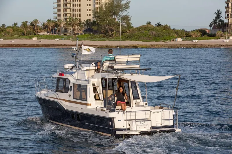  Yacht Photos Pics 2026 Ranger Tugs R-29 CB cruising near a sandy beach with palm trees.