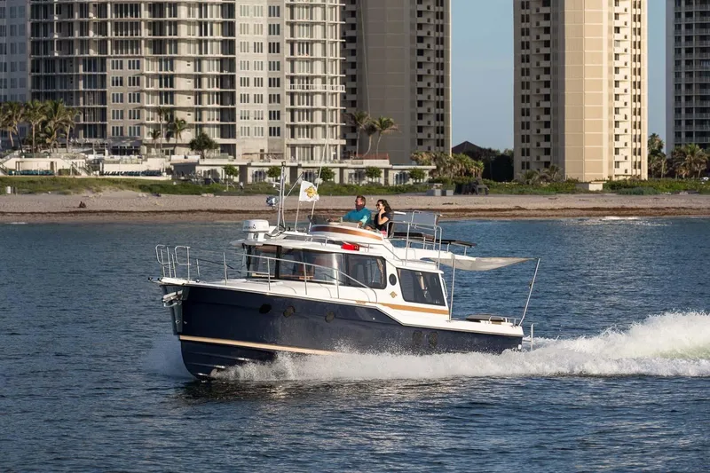  Yacht Photos Pics 2026 Ranger Tugs R-29 CB cruising near coastal high-rise buildings.