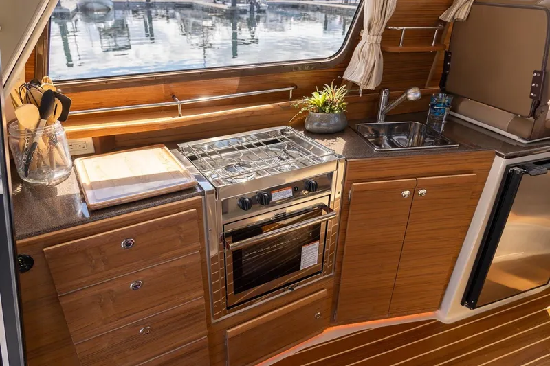  Yacht Photos Pics 2026 Ranger Tugs R-29 CB galley with stove, sink, and wooden cabinetry.