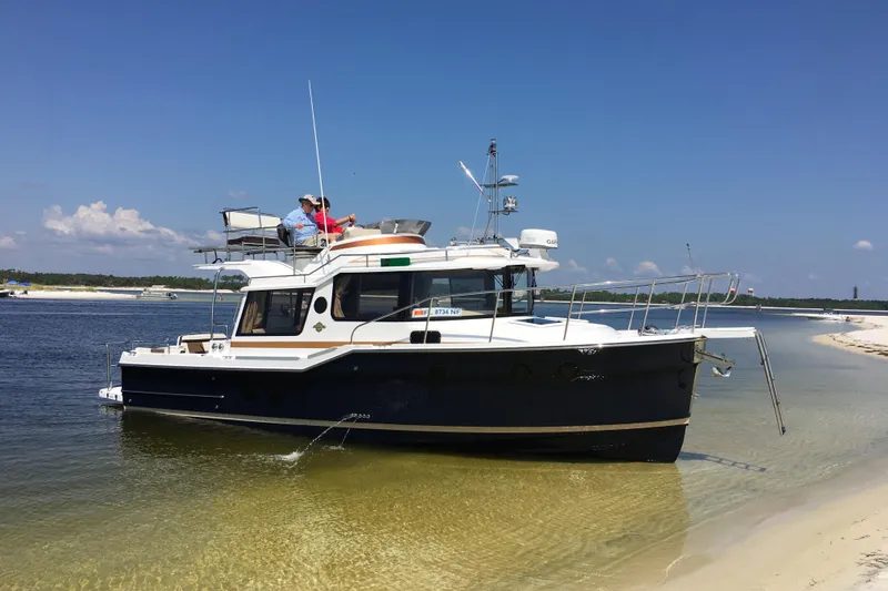  Yacht Photos Pics 2026 Ranger Tugs R-29 CB boat anchored on sandy shore under clear blue sky.