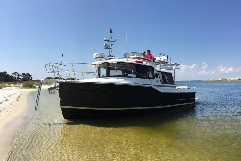  Yacht Photos Pics 2026 Ranger Tugs R-29 CB boat docked on a sandy beach under clear blue skies.