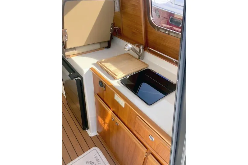  Yacht Photos Pics 2021 Ranger Tugs R-25 galley with wooden cabinetry, sink, and compact appliances.