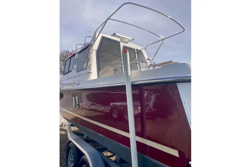  Yacht Photos Pics 2021 Ranger Tugs R-25 boat with red hull on a trailer, side view.