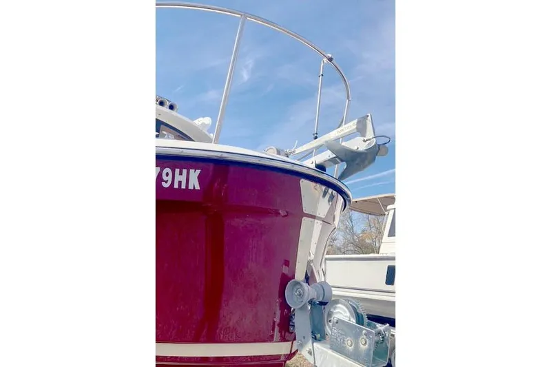  Yacht Photos Pics 2021 Ranger Tugs R-25 boat with red hull and visible anchor, under clear blue sky.