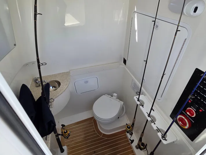 No Name Yacht Photos Pics 2021 Regulator 31 CC boat interior with toilet, fishing rods, and control panel.