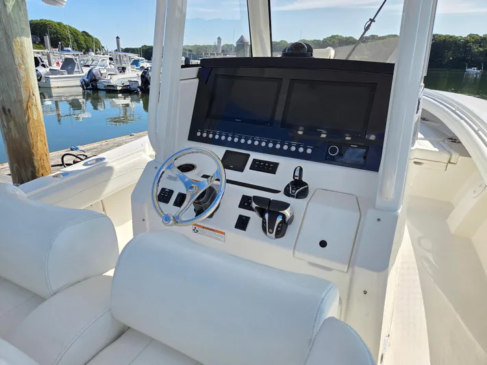 No Name Yacht Photos Pics 2021 Regulator 31 CC boat console with dual screens and steering wheel at marina.