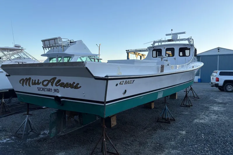  Yacht Photos Pics Custom 1994 workboat "Miss Alexis" on stands, white hull, green bottom, docked in a boatyard.