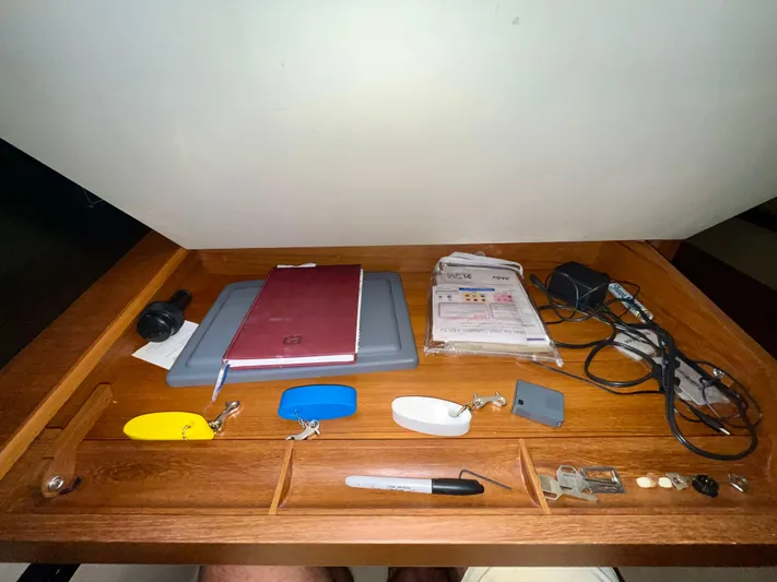 Intrepid II Yacht Photos Pics Wooden desk with assorted items: notebook, cables, keychains, and a pen, on an Island Packet 465 yacht.