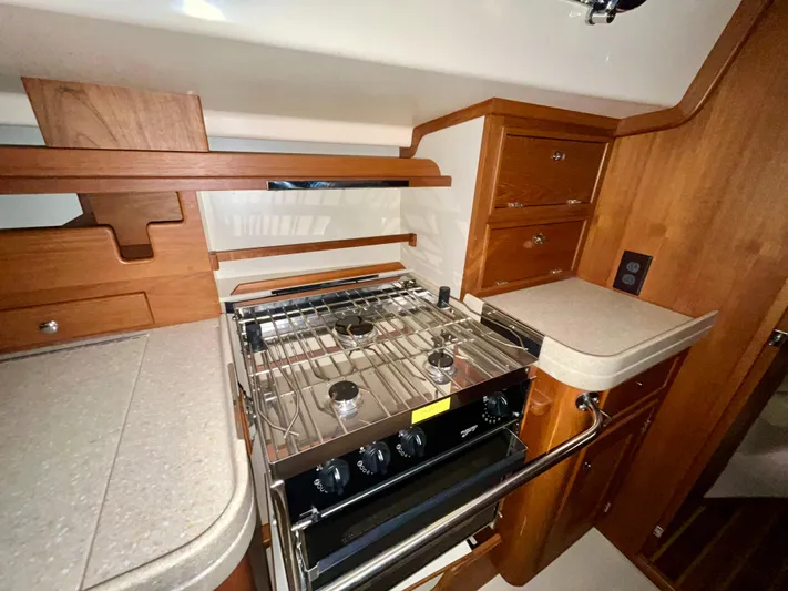 Intrepid II Yacht Photos Pics 2008 Island Packet 465 yacht kitchen with stove, wooden cabinetry, and countertops.