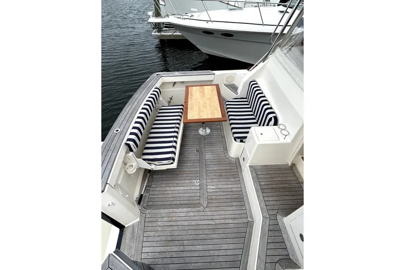  Yacht Photos Pics 2006 Sabre 38 Hard Top Express boat deck with striped seating and wooden table.