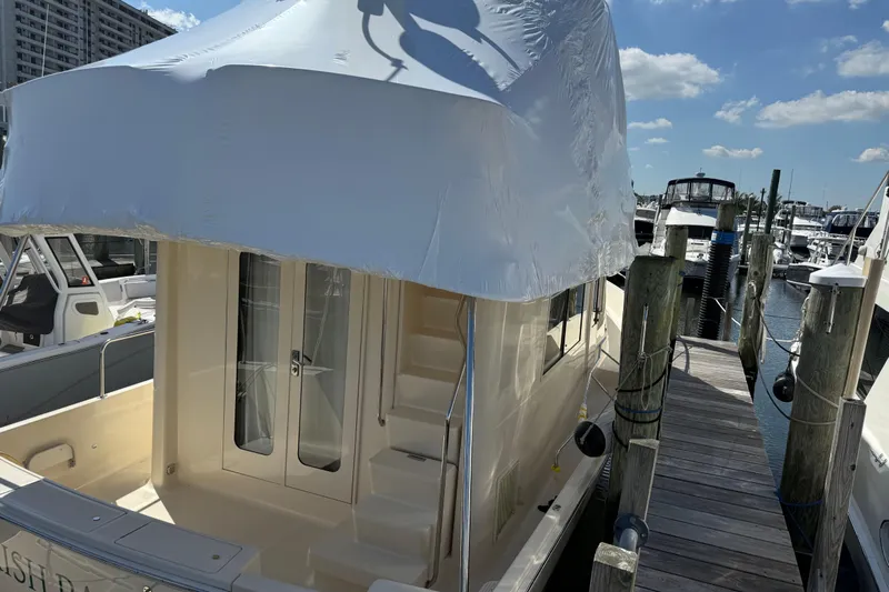  Yacht Photos Pics 2006 Mainship 34 Trawler docked, covered with white tarp, sunny marina setting.